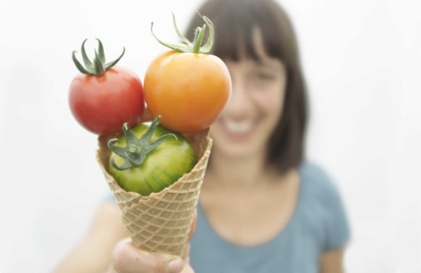 Bild mit Tomaten in einem Eis-Cornet. Im Hintergrund eine Person, die das Cornet hält.