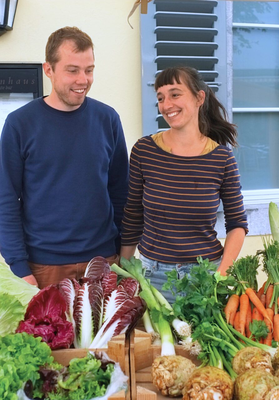 Portrait von Claude Brechbühl und Ronja Schlotterbeck hinter ihrem Bio-Gemüse Stand am Abendmarkt Thun.